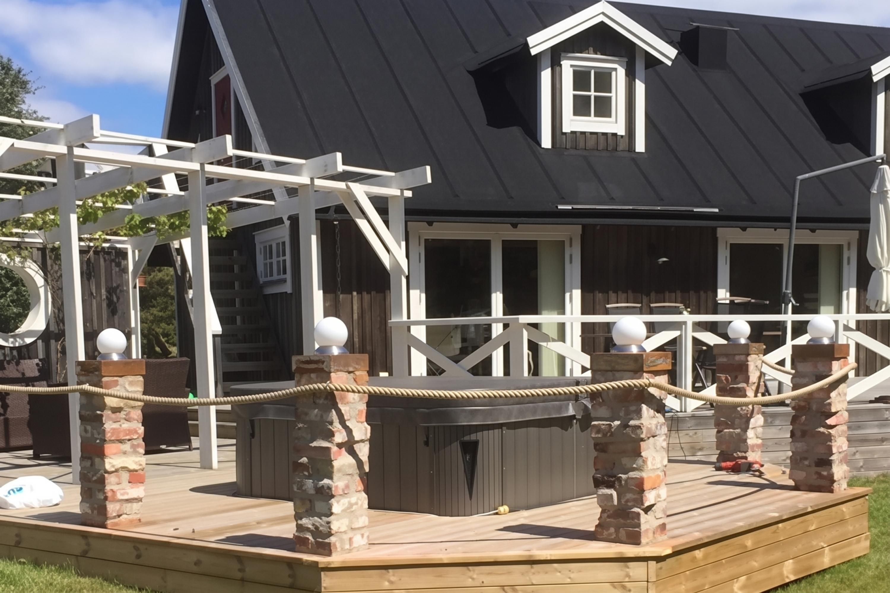 A wooden deck with a rope barrier, a brick chimney, and a white railing.