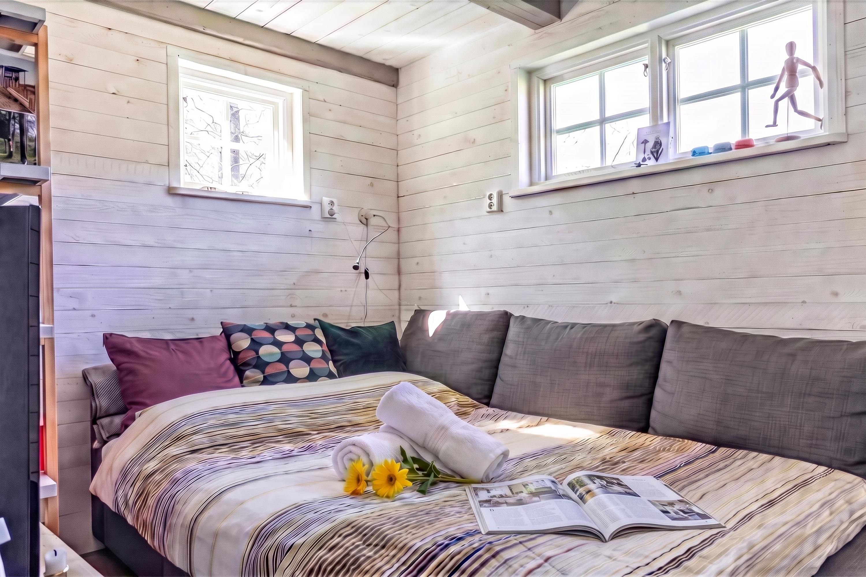 A bedroom with a bed, pillows, a window, and a book.
