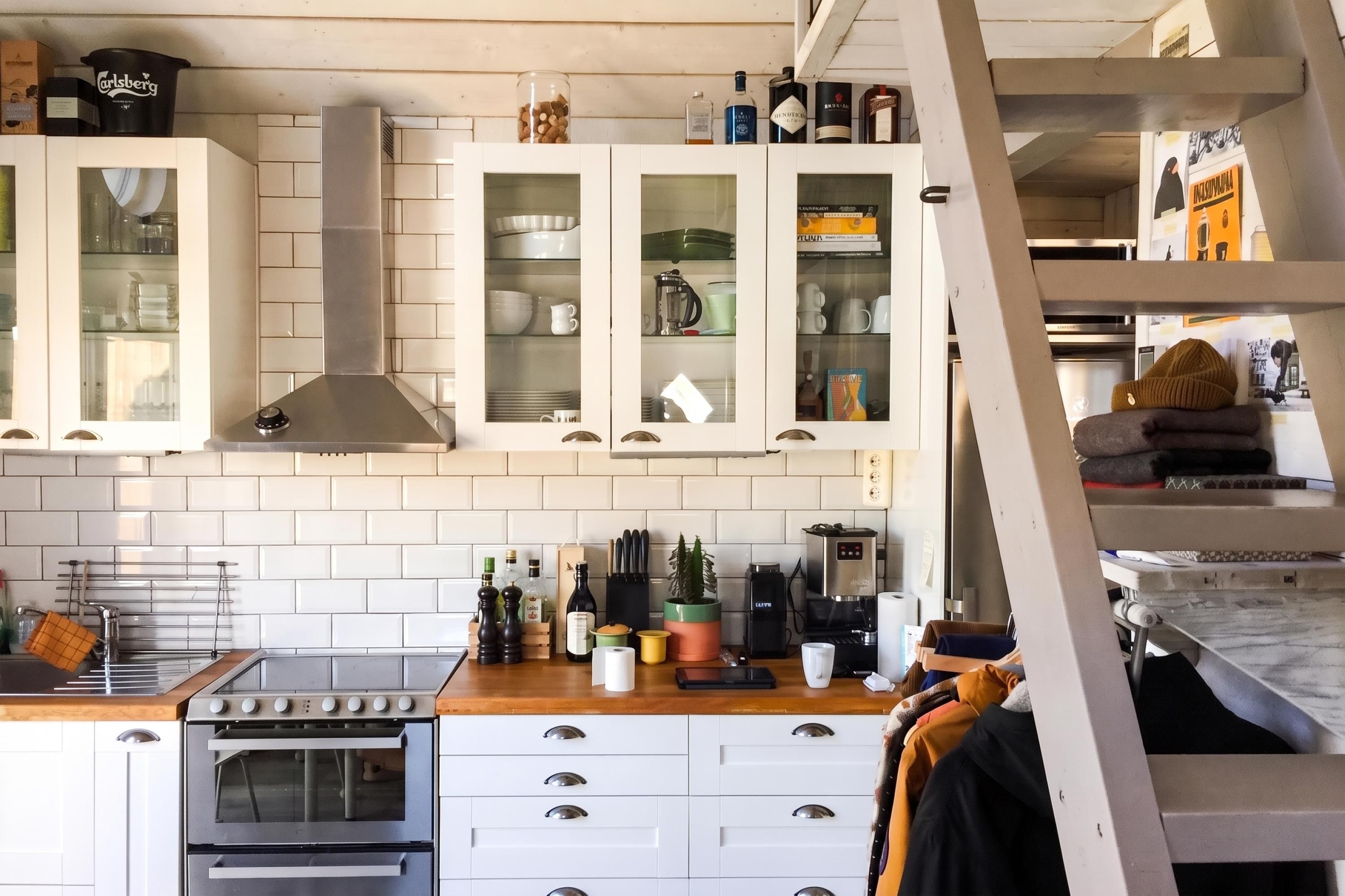 A kitchen with white cabinets, a stainless steel range hood, and a built-in oven.
