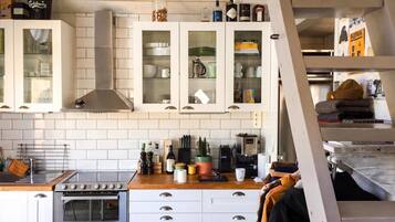 A kitchen with white cabinets, a stainless steel range hood, and a built-in oven.