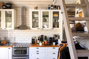 A kitchen with white cabinets, a stainless steel range hood, and a built-in oven. - The Aspö Island Hideaway, Drottningskär, Sweden (Drottningskär)