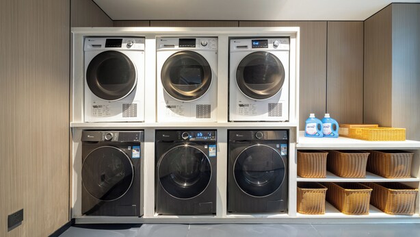 A laundry room with multiple washing machines and baskets. - Baihe yiting jiudian (Foshan)