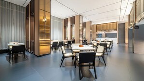 A modern hotel lobby with multiple dining tables and chairs, a reception area, and a kitchen in the background. - Baihe yiting jiudian (Foshan)