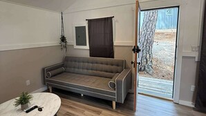 Ett modernt vardagsrum med en soffa, ett runt bord med en växt och en skjutdörr i glas som leder ut.