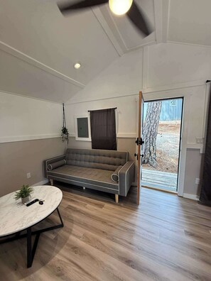 Ein modernes Wohnzimmer mit einer Couch, einem runden Tisch mit einer Pflanze und einer Schiebetür zum Garten.
