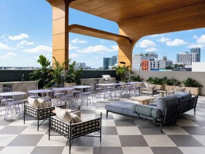 A rooftop terrace with outdoor seating, a view of the city skyline, and a checkered floor.