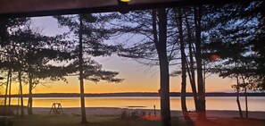 A lakeside view with trees, a swing set, and a row of chairs. - Spacious 8-bedroom waterfront estate on lake Noquebay in peaceful Wausaukee (Wausaukee)