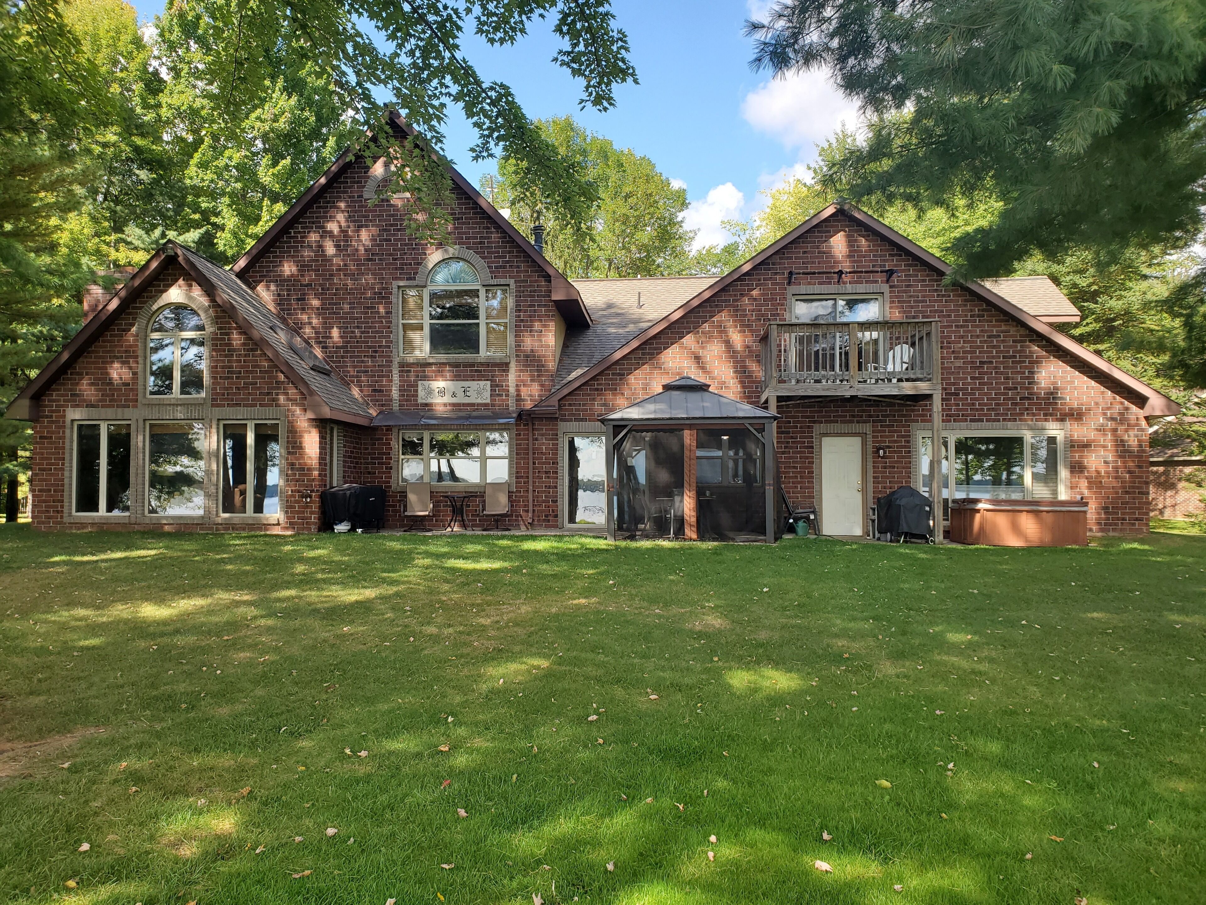 Een twee verdiepingen tellend bakstenen huis met een overdekte patio, een garage en een omheinde tuin.
