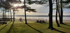 A lakeside view with trees, a swing set, and a picnic table. - Spacious 8-bedroom waterfront estate on lake Noquebay in peaceful Wausaukee (Wausaukee)