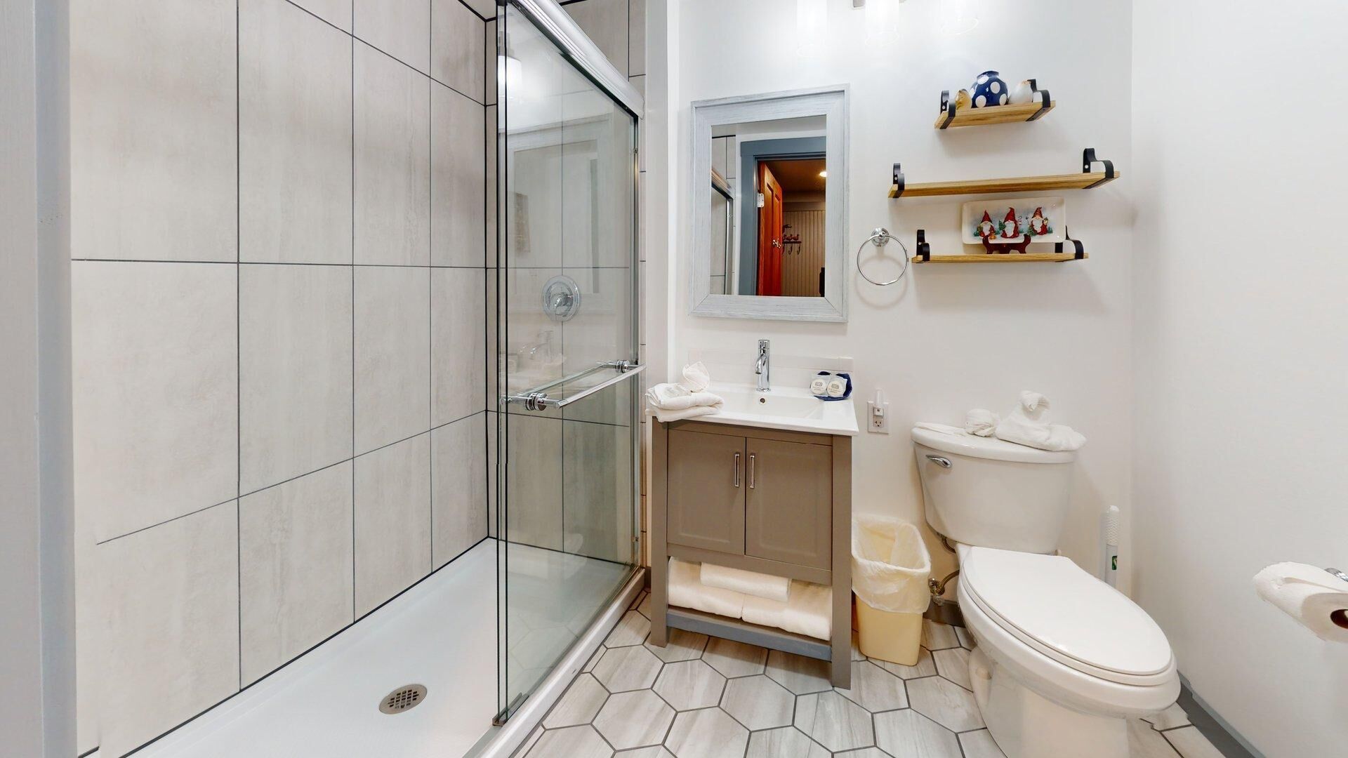 A bathroom with a glass shower enclosure, a sink with a mirror, and a toilet.