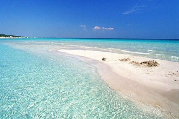 Une plage à l’eau turquoise et au sable blanc.