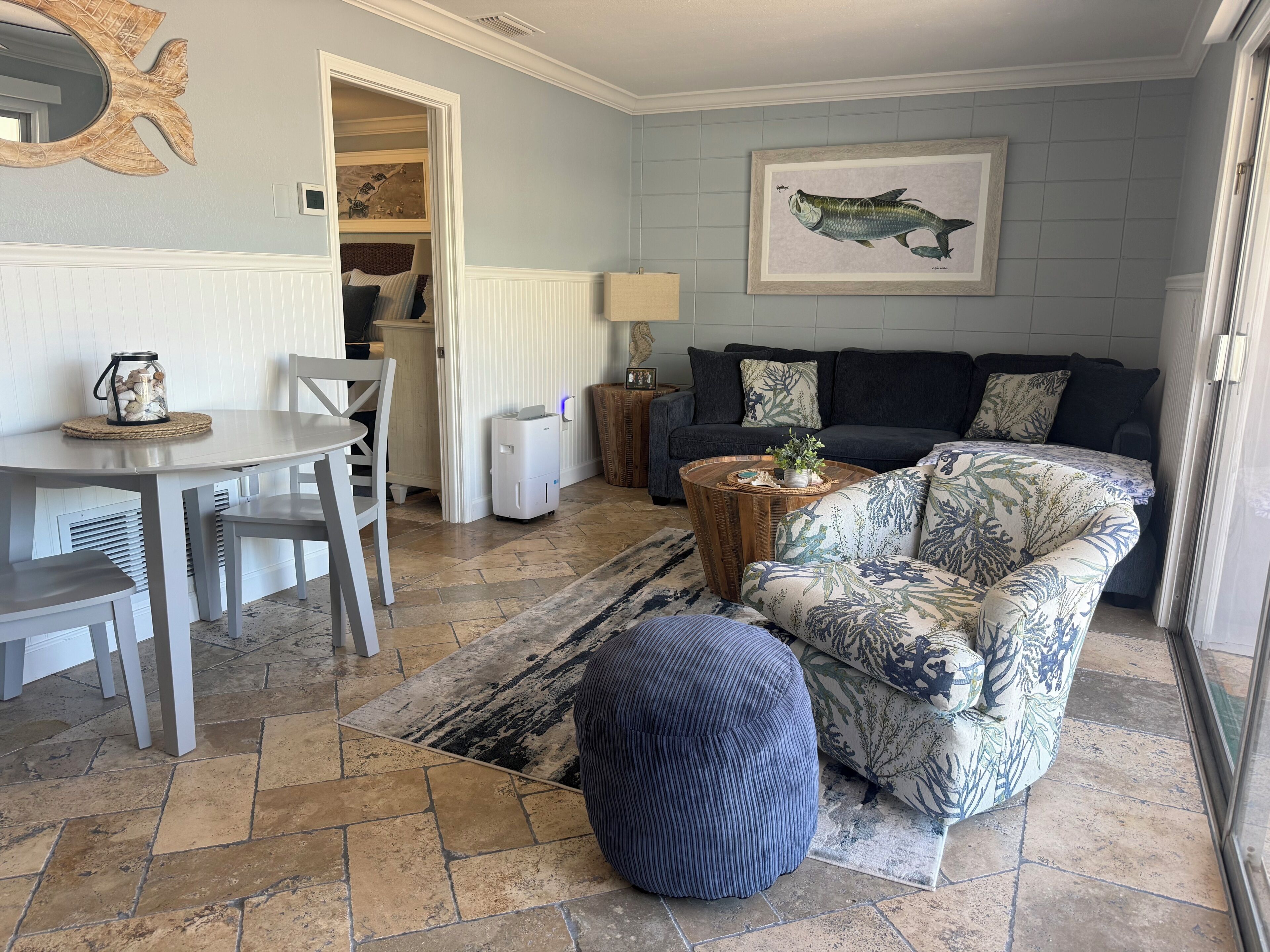 Een woonkamer met een bank, een poef, een salontafel en een eethoek met stoelen en een tafel.
