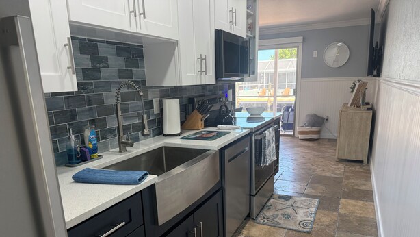 Una cocina moderna con electrodomésticos de acero inoxidable, un salpicadero de azulejos y vistas al exterior.