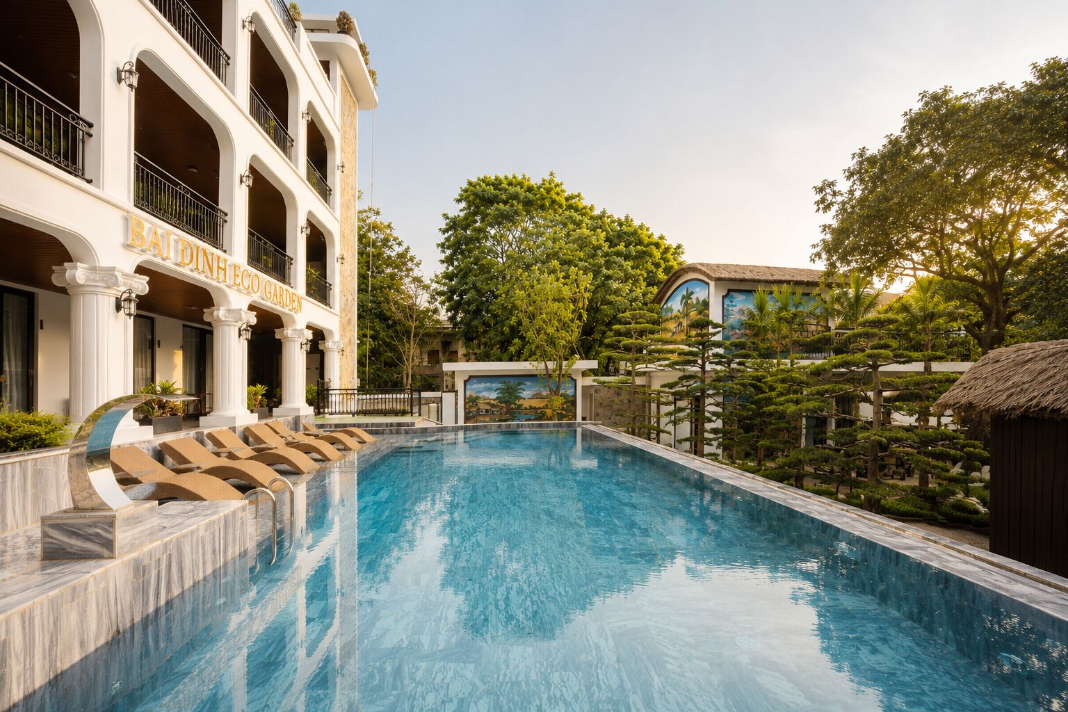 A swimming pool with a building labeled 'BAIDINH ECO GARDEN' in the background.