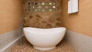 Un baño con una bañera independiente, ducha y perchero para toallas.
