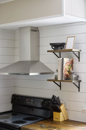 A kitchen with a stove, a range hood, and a knife block on the counter. - Private Retreat:: Hot Tub, Sauna & Fire Pit (Logan)