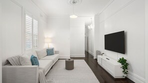 A modern living room with a sofa, a TV, a lamp, and a plant. - The Leichhardt Hideaway on Francis St (Leichhardt)