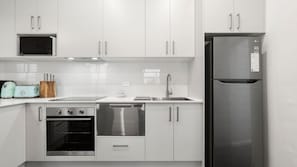 Eine moderne Küche mit weißen Schränken, Edelstahlgeräten, einer Mikrowelle, einem Toaster und einem Kühlschrank.