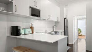 A modern kitchen with white cabinetry, a built-in microwave, a toaster, and a sink. - The Leichhardt Hideaway on Francis St (Leichhardt)