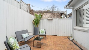 A patio with a brick floor, a white fence, and a potted plant. - The Leichhardt Hideaway on Francis St (Leichhardt)