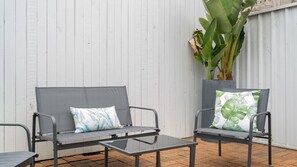 A patio with a metal-framed sofa and armchair, a glass-top table, and a potted plant. - The Leichhardt Hideaway on Francis St (Leichhardt)