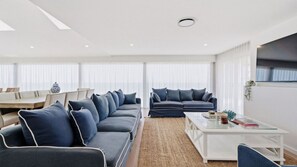 Ein modernes Wohnzimmer mit einem Ecksofa, einem Couchtisch und einem Essbereich mit Tisch und Stühlen.