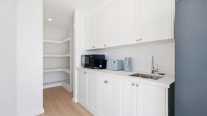 A modern kitchen with white cabinetry, a microwave, a toaster, and a kettle.