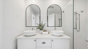 Een moderne badkamer met twee wastafels, een spiegel en een douche.