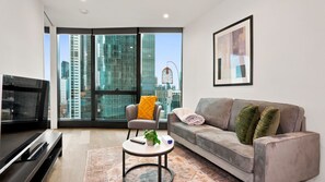 Una sala de estar moderna con un sofá, un sillón, una mesa de centro y un televisor.