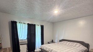 Ein Schlafzimmer mit einem Bett, einem Schreibtisch, einem Fenster mit Vorhängen und einer Heizung.