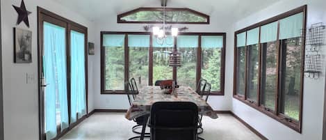 A dining room with a large table, chairs, and a chandelier.