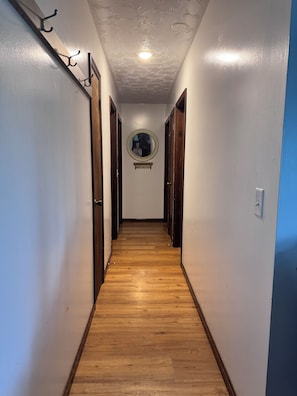 Un pasillo con piso de madera, un espejo redondo en la pared y una lámpara en el techo.