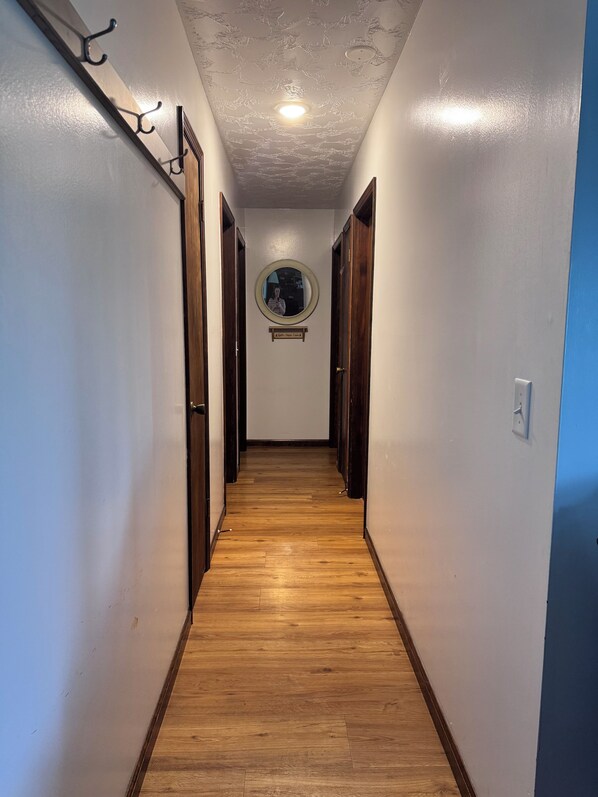 Un pasillo con piso de madera, un espejo redondo en la pared y una lámpara en el techo.