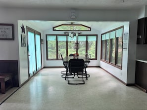 A dining area with a table and chairs, large windows, and a chandelier.