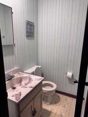 Un baño con inodoro, lavamanos y espejo.