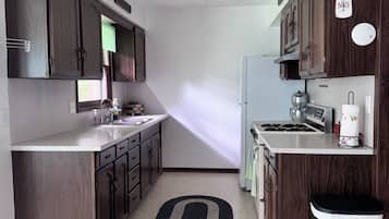 A modern kitchen with dark wood cabinets, a stainless steel sink, and a black trash bin.