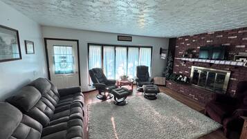Una sala de estar con chimenea, un sofá, un sillón reclinable y una alfombra.