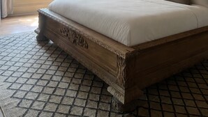 Camera da letto con un letto grande, una testiera in legno, una finestra con vetri colorati e vista sul verde.