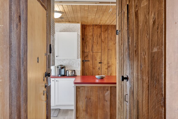 Una cocina con armarios de madera, encimera roja y electrodomésticos blancos.