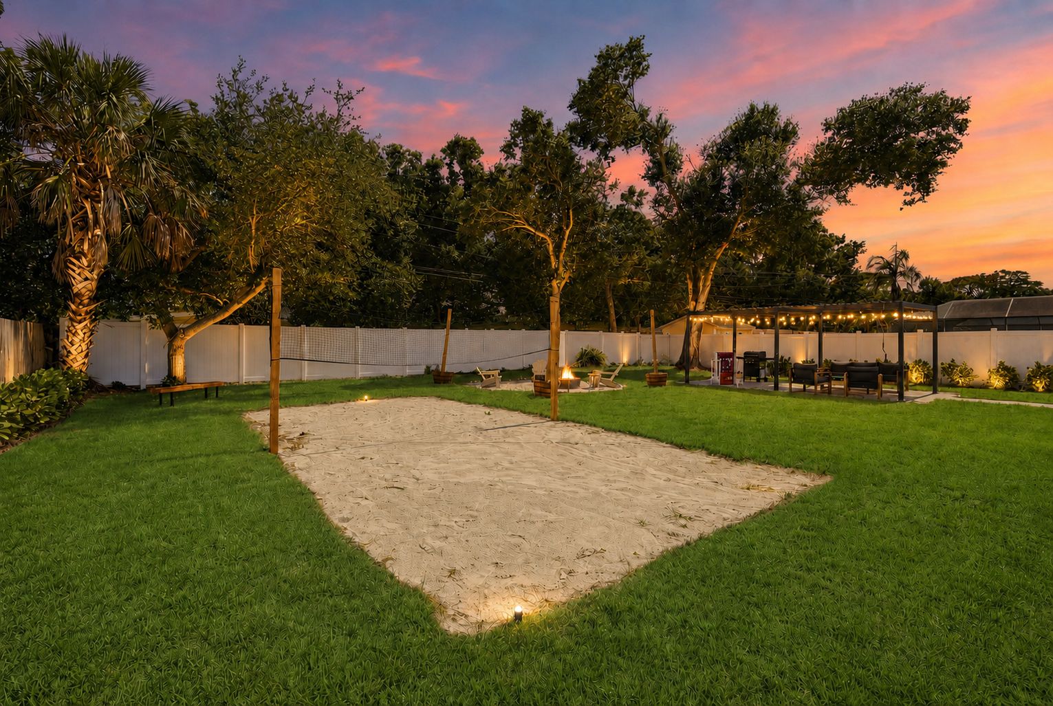 A backyard with a sandpit, a wooden bench, a fire pit, and a covered seating area with string lights.