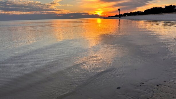 A beach with calm water reflecting the sunset. - No Egrets: 2 BR Condo Gulf Views, Pool, Walk to Beach, Golf Cart District (Long Beach)