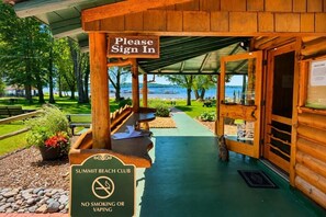 A wooden cabin with a 'Please Sign In' sign, a 'No Smoking or Vaping' sign, and a view of the beach. - Family Getaway at Shanty Creek | Pools, Skiing & Lake Views (Bellaire)
