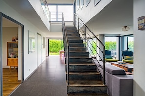 Un interior moderno con una escalera, un sofá y una zona de comedor.