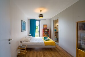 Ein Schlafzimmer mit Bett, Nachttisch, Kleiderschrank und einer Tür, die auf einen Balkon führt.