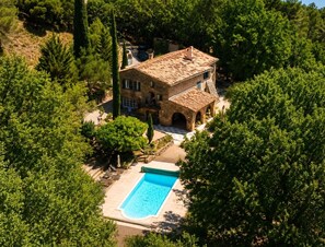 Eine Steinvilla mit Swimmingpool, umgeben von Bäumen.