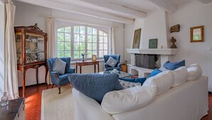 A living room with a white sofa, blue armchairs, a wooden cabinet, and a fireplace. - Le Mas de Villecroze - Belle piscine extérieure (Villecroze)