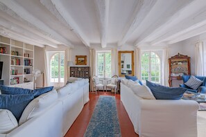 Ein Zimmer mit weißen Sofas, einem blauen Teppich und einem Bücherregal.