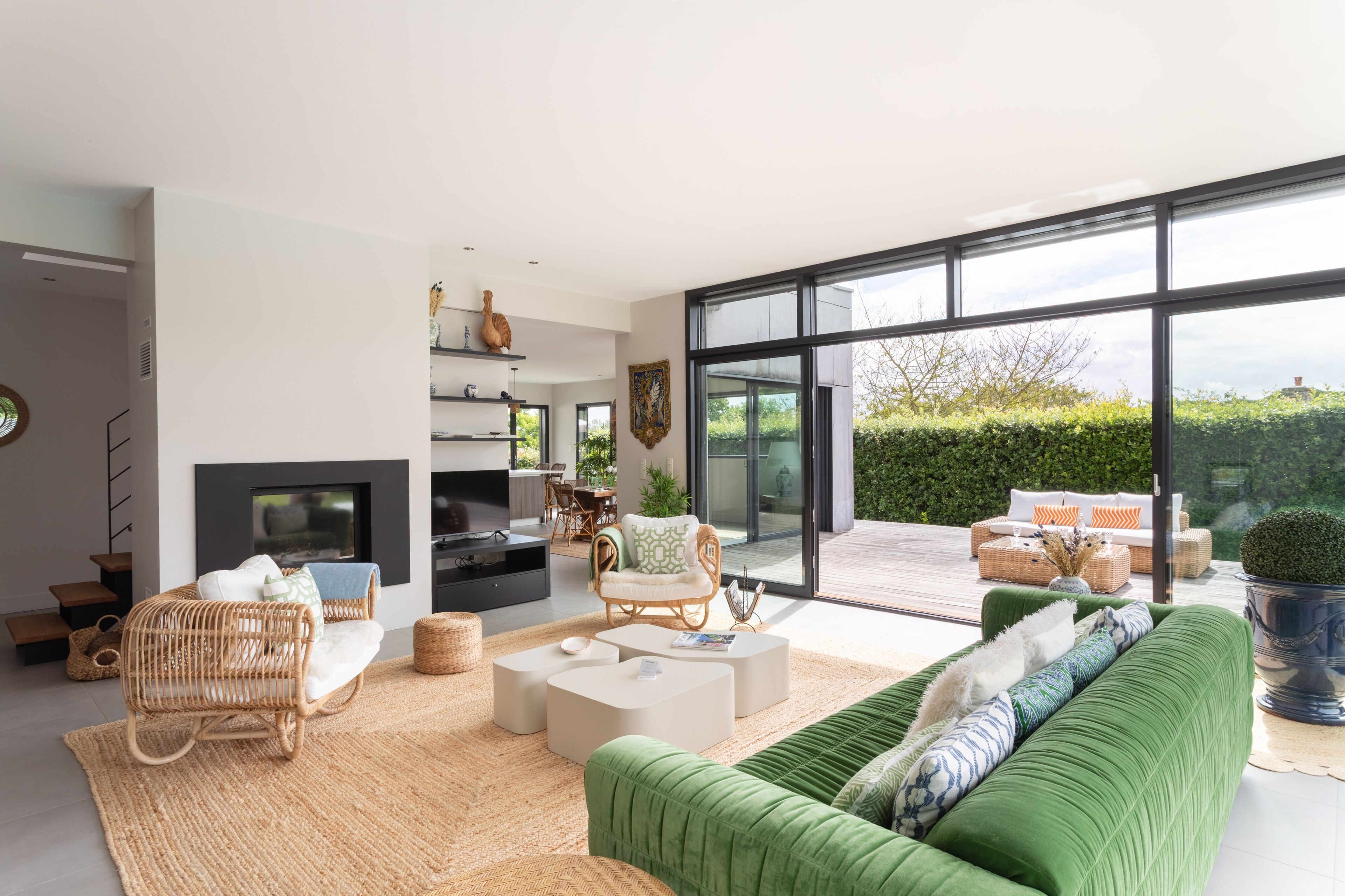 Un salon moderne avec une cheminée, de grandes fenêtres et un canapé vert.