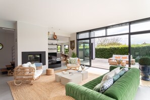Una sala de estar moderna con chimenea, ventanas amplias y un sofá verde.