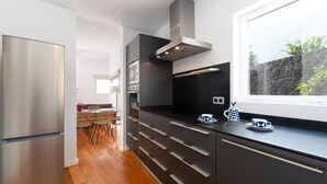 Una cucina moderna con frigorifero in acciaio inossidabile, pensili neri e una finestra vista su un paesaggio roccioso.